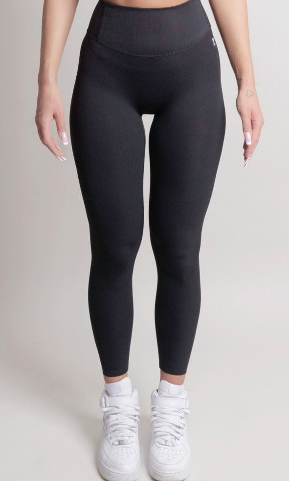 Person wearing black leggings and white sneakers on a plain background