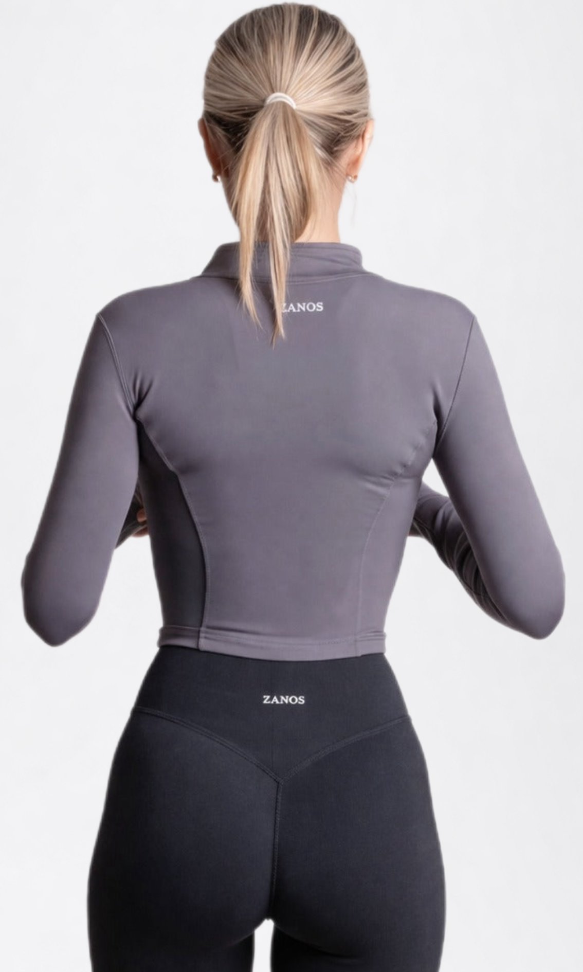 Person wearing a gray athletic jacket and black leggings with 'ZANON' branding on a white background