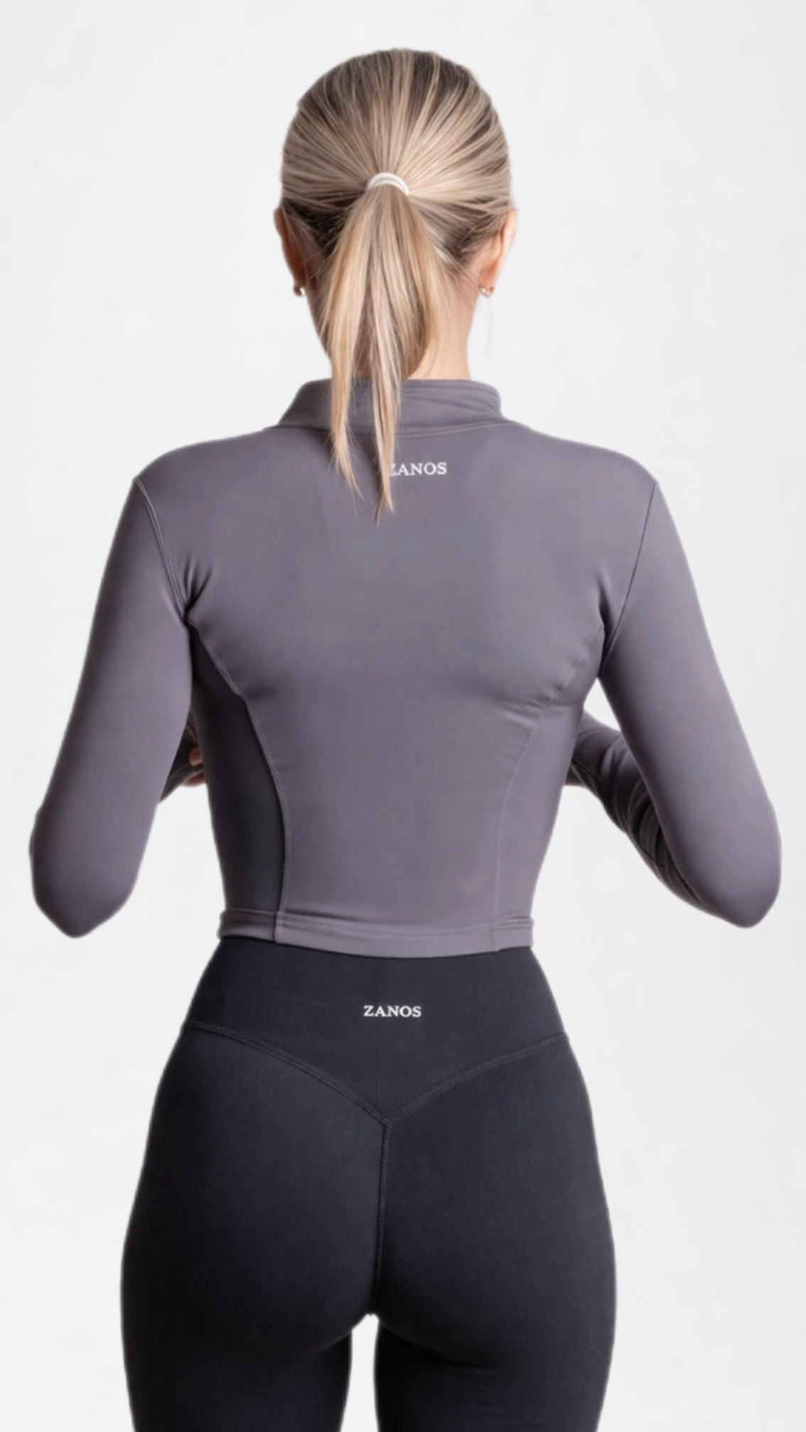 Person wearing a gray athletic jacket and black leggings with 'ZANON' branding on a white background