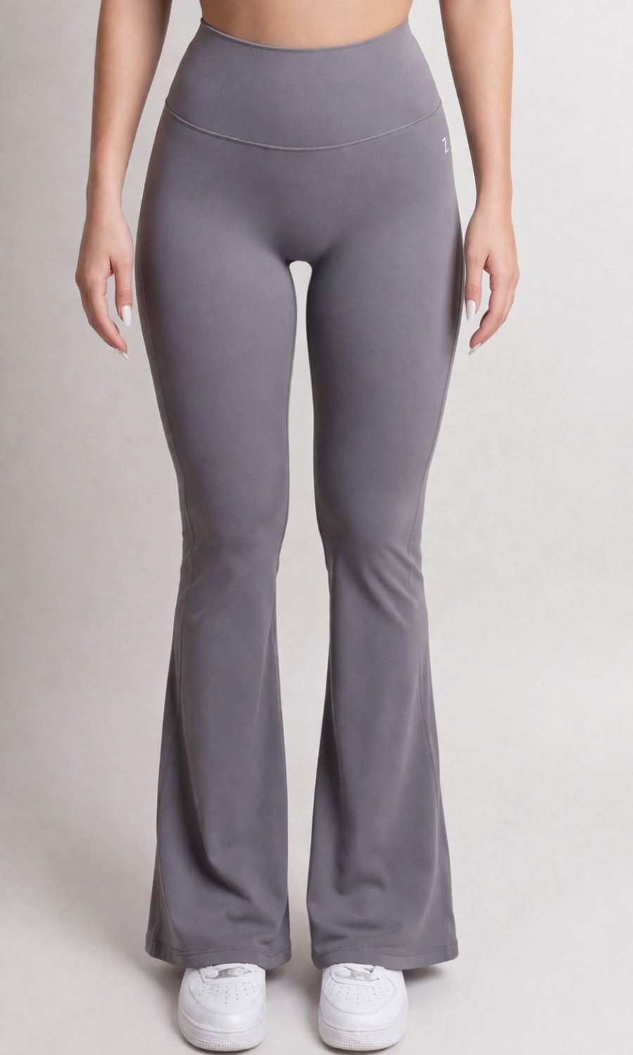 Person wearing gray flared leggings on a plain background