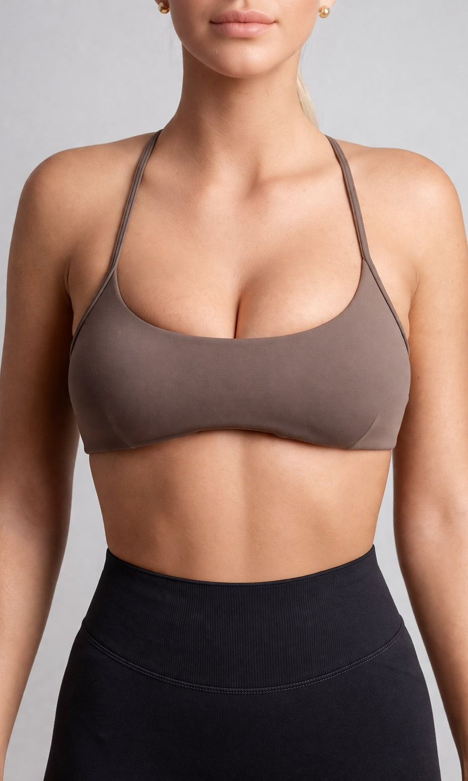 Person wearing a brown sports bra and black leggings against a gray background