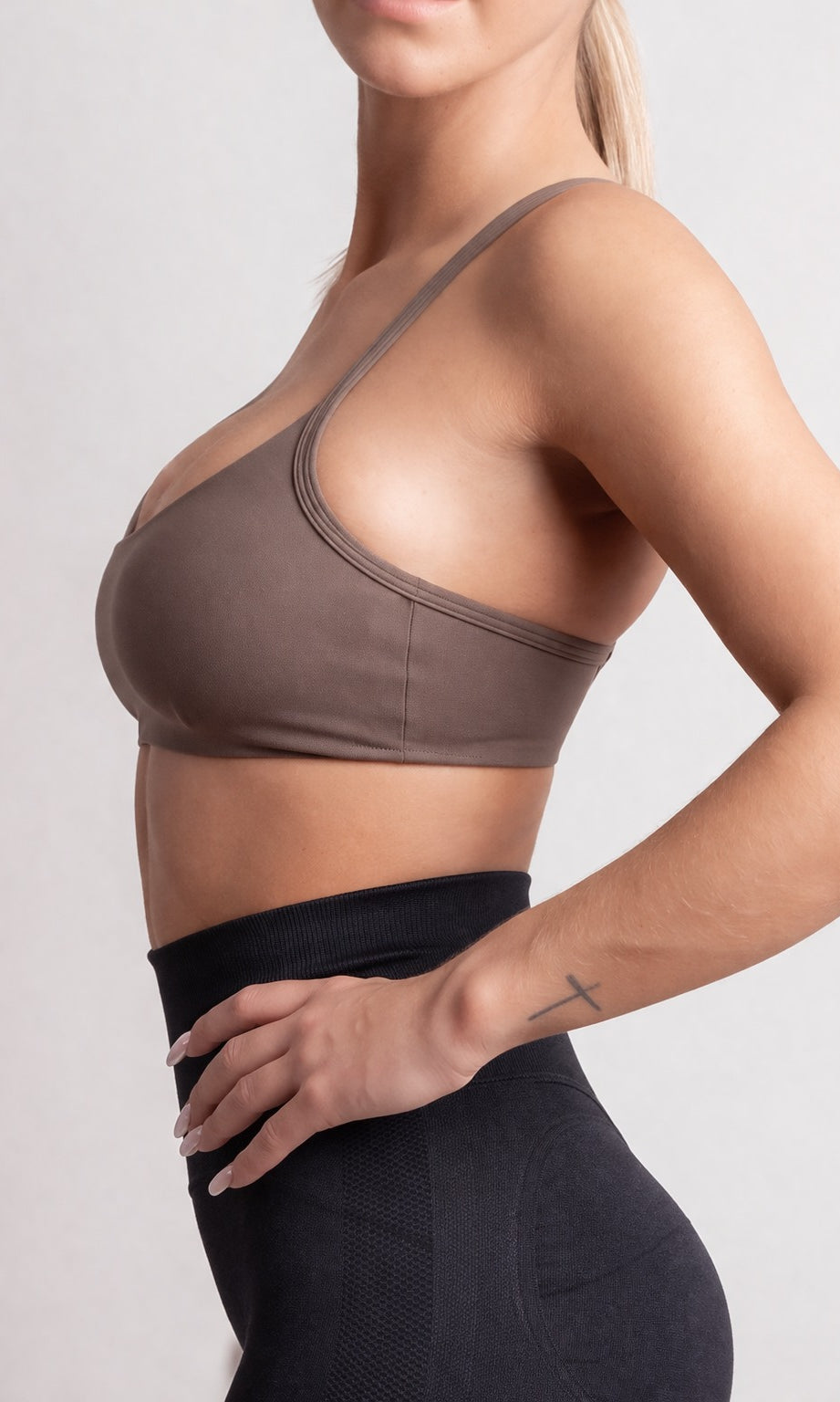 Person wearing a brown sports bra and black leggings on a plain background