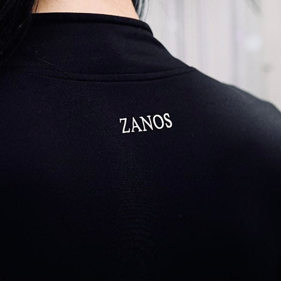 Person wearing a black shirt with 'ZANOS' branding, facing away from the camera.