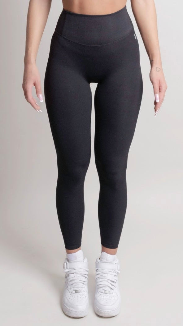 Person wearing black leggings and white sneakers on a plain background