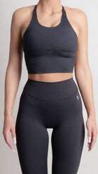 Person wearing a black sports bra and leggings set on a light gray background