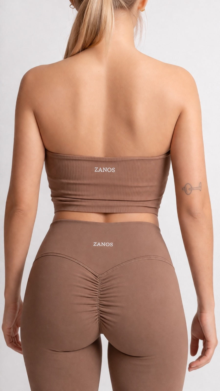 Person wearing a brown sports outfit with 'ZANOS' branding on a white background