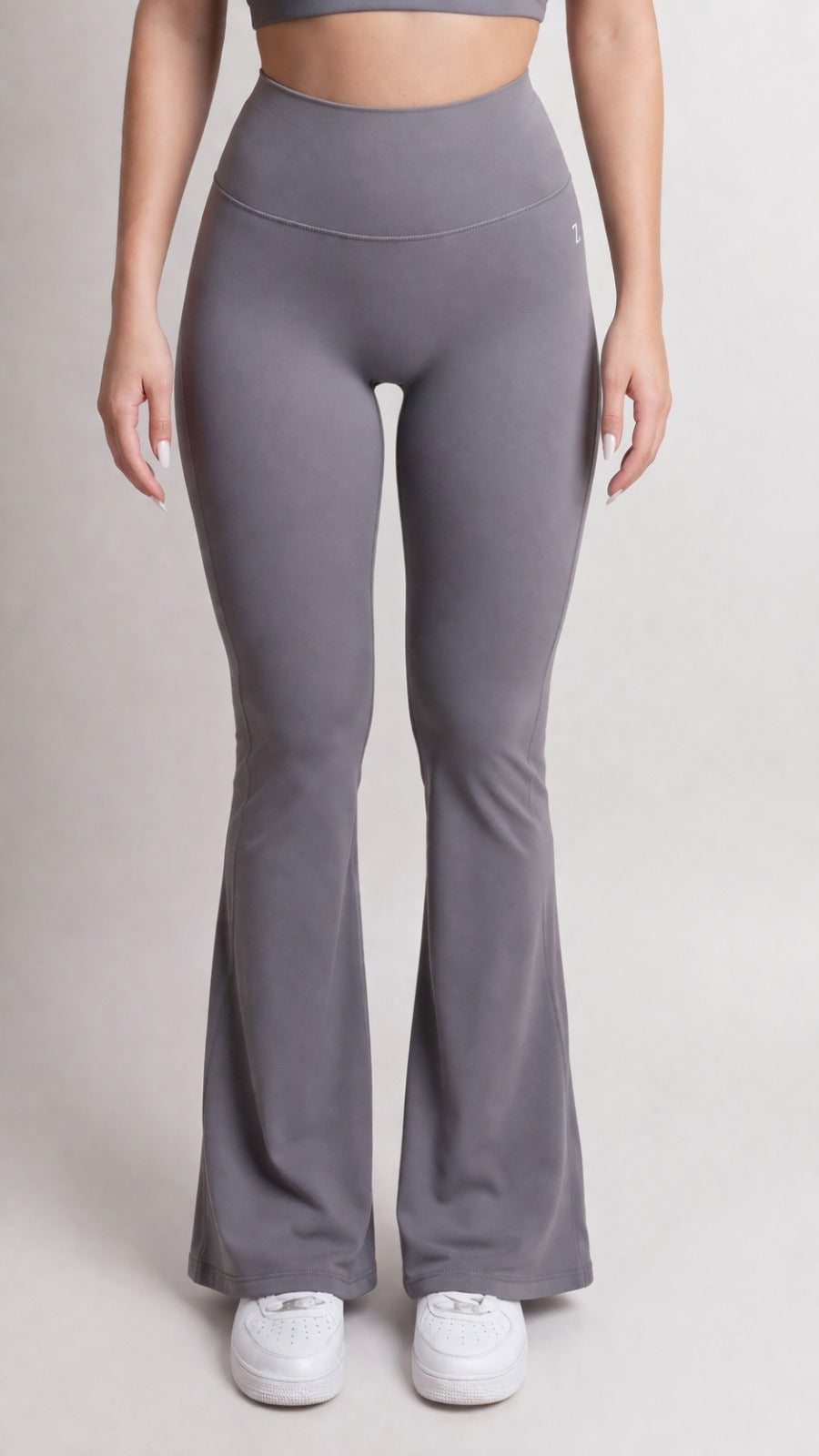 Person wearing gray flared leggings on a plain background
