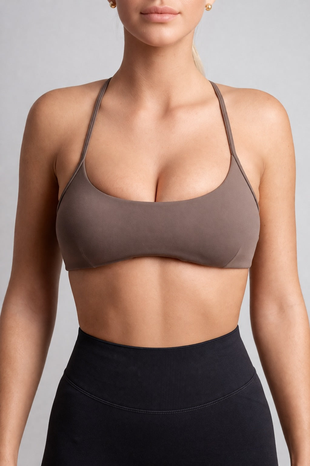 Person wearing a brown sports bra and black leggings against a gray background