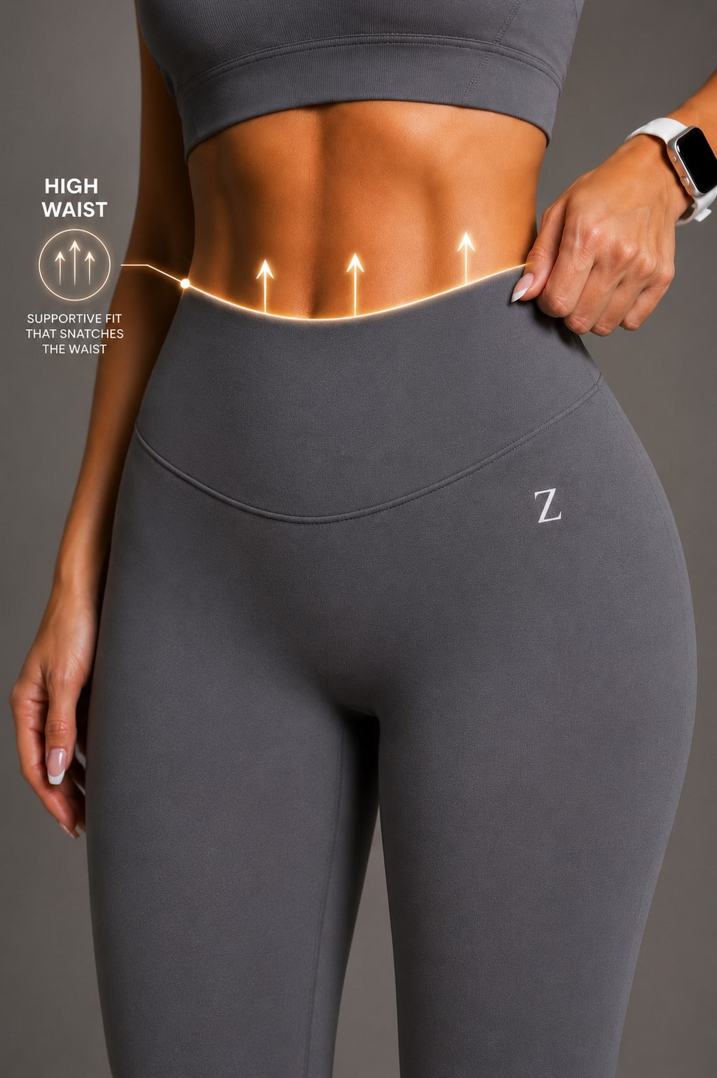 A close-up of a model wearing a dark gray sports bra and high-waisted leggings with a small white 'Z' logo on the hip. The image includes graphic overlays showing a high waistline with arrows pointing upward and text reading 'HIGH WAIST' and 'SUPPORTIVE FIT THAT SHAPES THE WAIST'.
