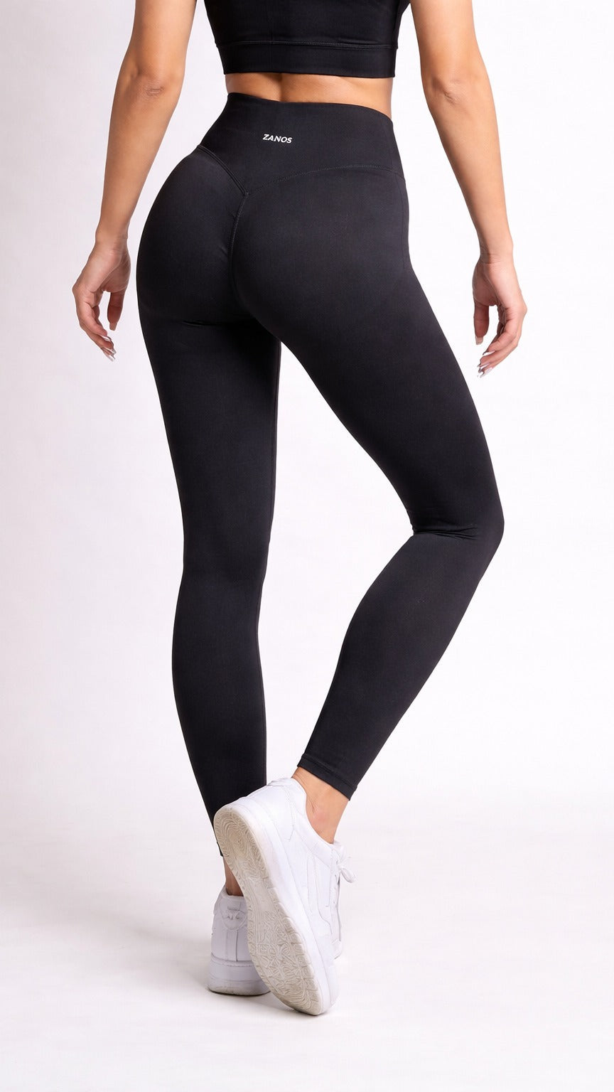 Person wearing black leggings and white sneakers on a light gray background