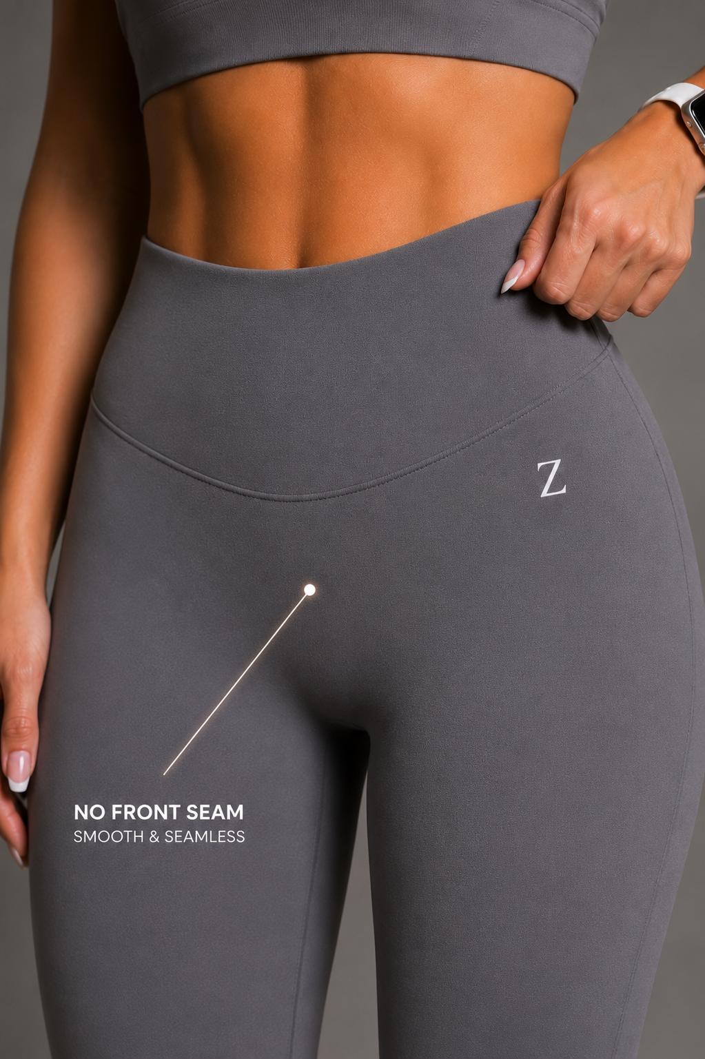 Close-up of a model wearing dark gray high-waisted leggings with a white 'Z' logo on the hip and text reading 'NO FRONT SEAM SMOOTH & SEAMLESS,' showing the waistband design.